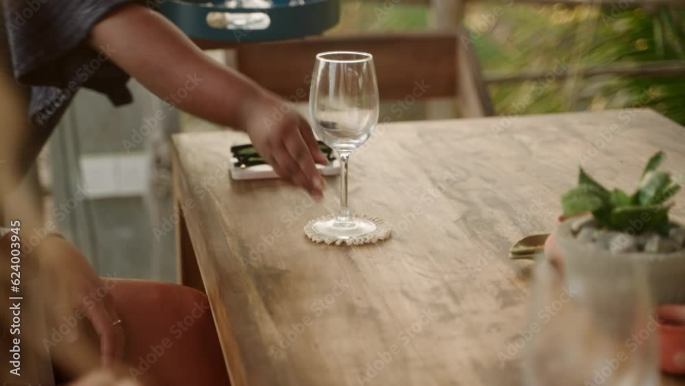 Waiter puts empty wine glasses on the table in front of female friends. Waitress with a tray brings goblets to women customers placing them on authentic coasters. Serving glasses for alcohol drinks Waiter puts empty wine glasses on the table in front of female friends. Waitress with a tray brings goblets to women customers placing them on authentic coasters. Serving glasses for alcohol drinks