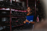 Happy smiling african american worker woman wear spectacles holding clipboard standing in factory auto parts. female employee business warehouse motor vehicle checking product auto parts.