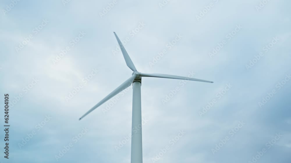 Windmill. Wind power turbine generating clean renewable energy. Central composition. Clouds at background. Green energy concept. 4K, UHD Windmill. Wind power turbine generating clean renewable energy. Central composition. Clouds at background. Green energy concept. 4K, UHD
