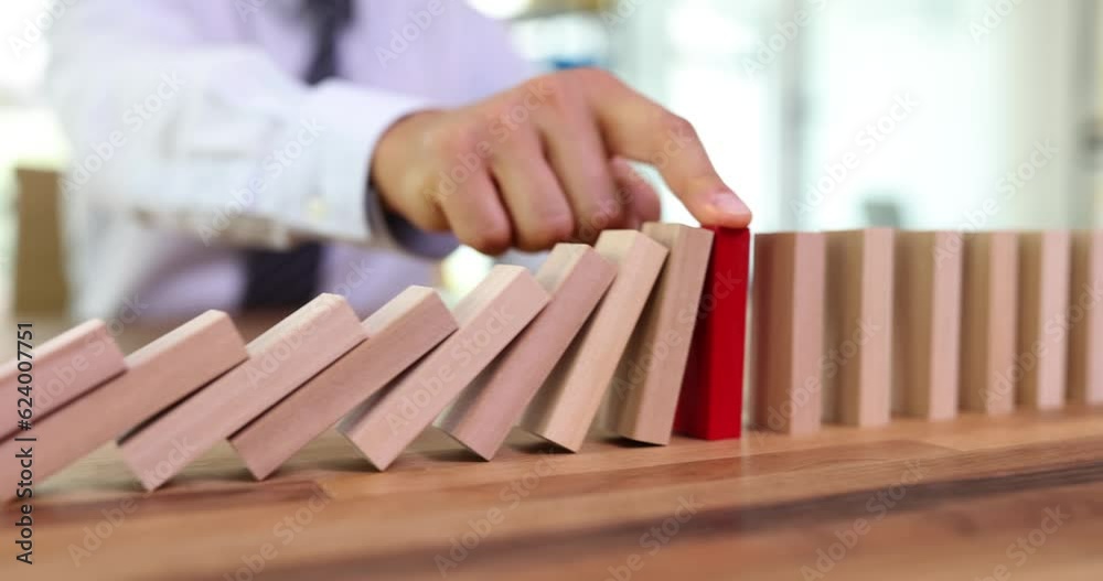 Business man protecting a wooden block from falling down planning and strategy at risk for business. Alternative and prevention