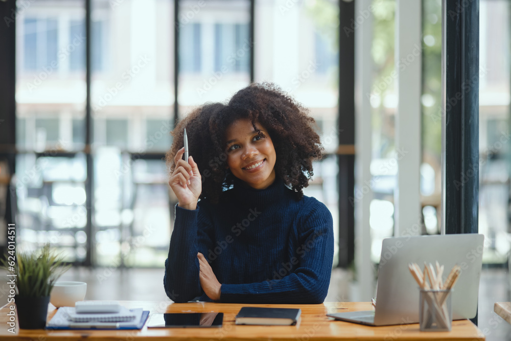 African American woman working and sitting at desk in office. African American woman working and sitting at desk in office.