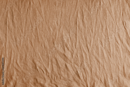 Wrinkled, crumpled brown fabric texture background. Wrinkled and creased abstract backdrop of cotton jersey textile, wallpaper with copy space, top view.
