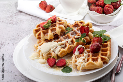 Viennese waffles with strawberries on a white dish on a light sunny background
