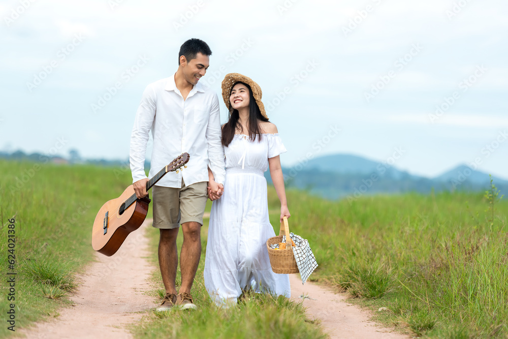 Lifestyle couple happy honeymoon in sunny time. Asian young couple sitting picnic and relax in the meadow in holiday. Romantic and In love. Lifestyle and Valentine concept Lifestyle couple happy honeymoon in sunny time. Asian young couple sitting picnic and relax in the meadow in holiday. Romantic and In love. Lifestyle and Valentine concept