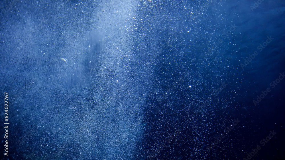 Air bubbles floating and rising up to the sea surface. Sun light shining through ocean. Abstract underwater background or backdrop