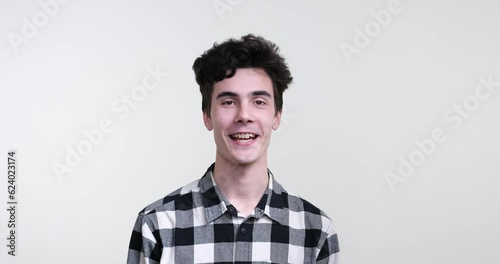 A charismatic curly-haired Caucasian man standing against a pristine white background. With a warm smile on his face, he nods his head in a resolute gesture, uttering a firm yes