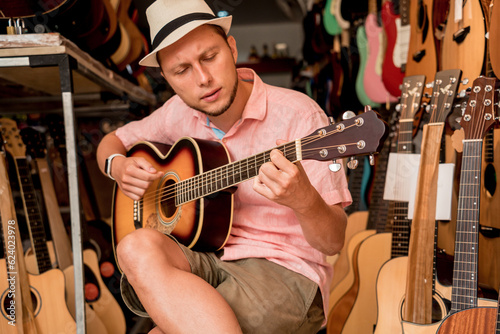 Young musician testing classical guitar in a guitar shop