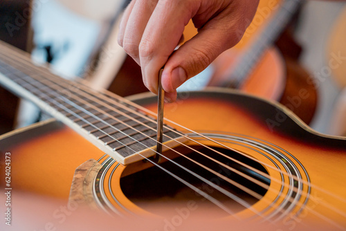 Young musician tuning a classical guitar in a guitar shop