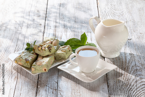 nougat with nuts on a white dish on a wooden table in the sun
