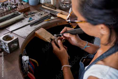 Young faemale jeweler polishing jewelry in workshop photo