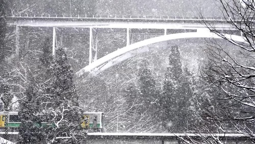 A Japanese Kiha series train running in winter. Dim lights shone on the snow. The background is Iron bridge.