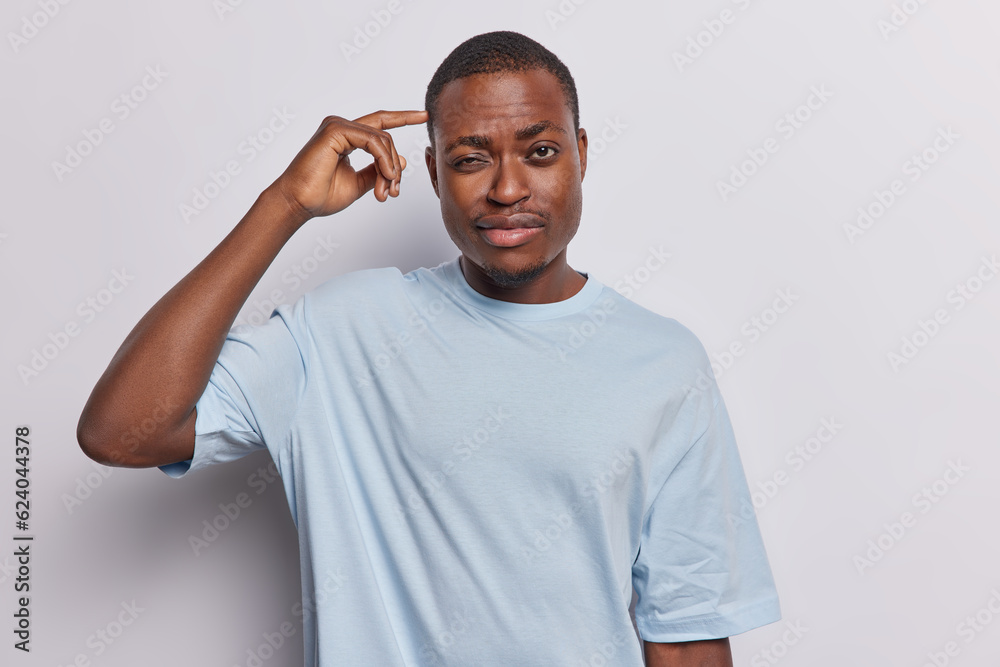 Waist up shot of thoughtful dark skinned man with beard keeps hand on temple considers something wears casual blue tshirt thinks about something isolated over white background. Let me think. Waist up shot of thoughtful dark skinned man with beard keeps hand on temple considers something wears casual blue tshirt thinks about something isolated over white background. Let me think.