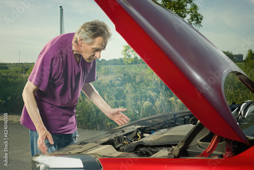 Pensioner checking state of his car with smoking engine