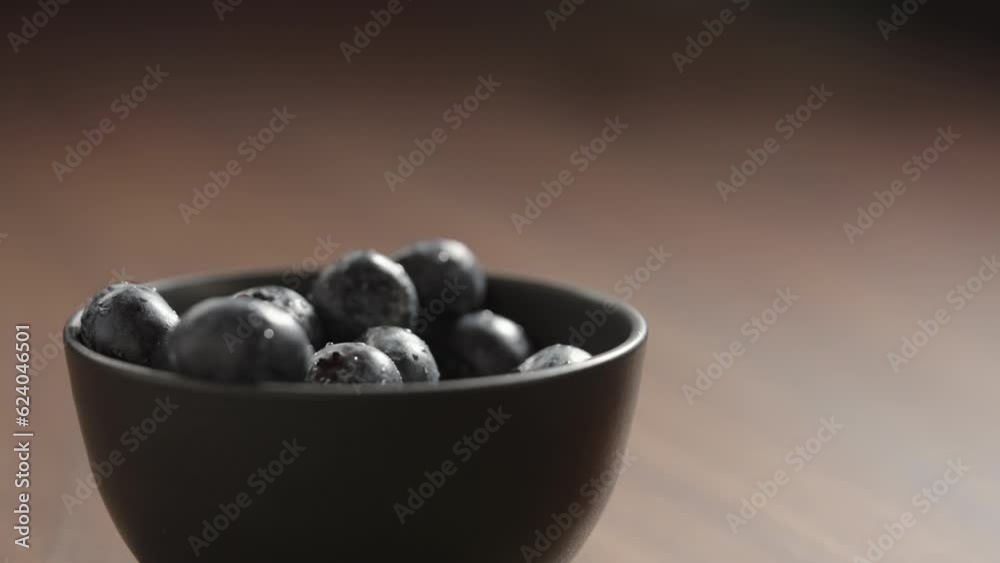 Slow motion fresh washed blueberries picked by man hand from black bowl Slow motion fresh washed blueberries picked by man hand from black bowl