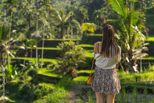 Back view of young stylish lady with rice terrace background. Discovering balinese agriculture and paddy fields