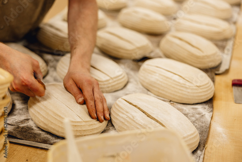 baker finishing sourdough loaves before putting them in the oven professional kitchen