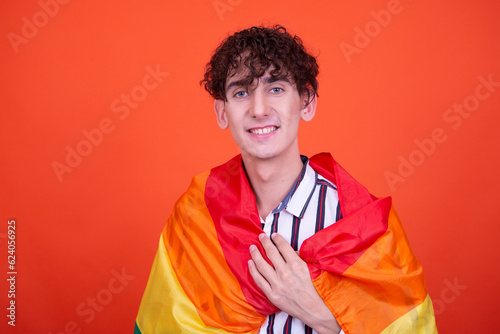 Young attractive guy posing in the studio on an orange background.
