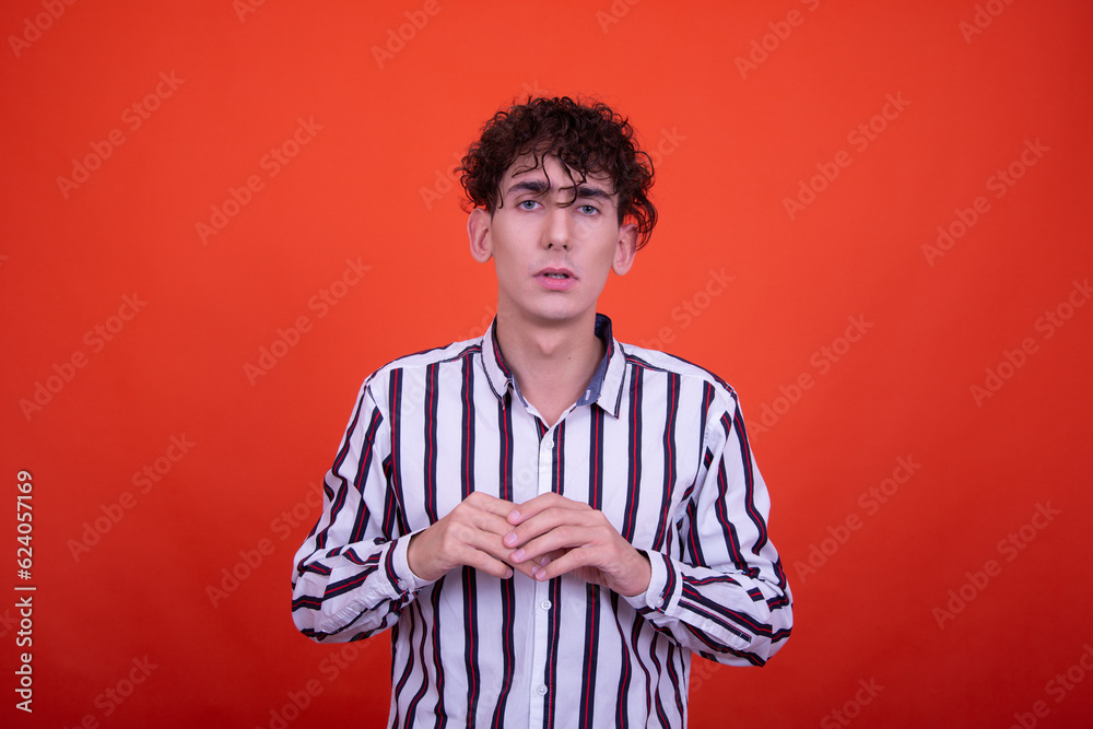 Young attractive emotional guy posing in the studio on an orange background.