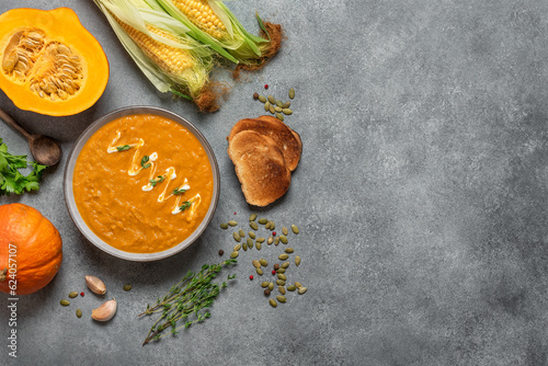 Pumpkin cream soup in a bowl with toasts on a gray rustic background. Thanksgiving concept. View from above.