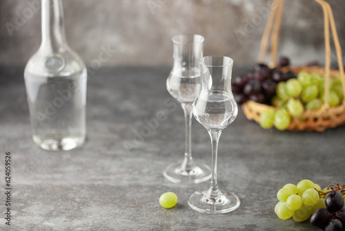 Grape vodka or grappa. Strong alcoholic drink in grappa glasses on the table. Fresh grapes