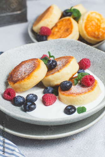 Cottage cheese pancakes with creamy sauce, raspberries and blueberries