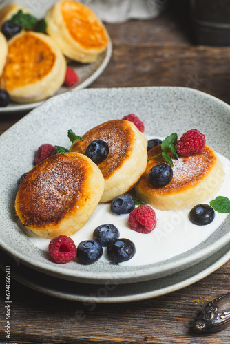 Cottage cheese pancakes with creamy sauce, raspberries and blueberries