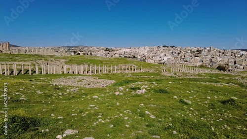 Jerash, Jordan: Panoramic footage of the Archaeological Site of the ancient Greco-Roman city of Gerasa famous for temples, amphitheater which contrasts with the modern city skyline photo