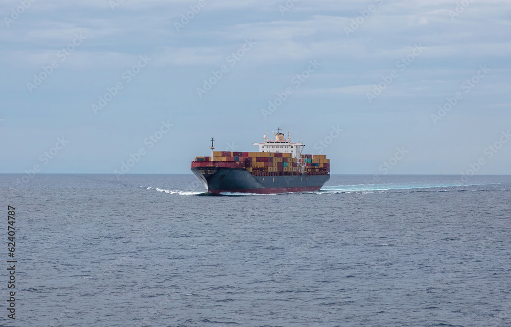 Container cargo ship full loaded in wavy sea reaches the port. Import export, water transport.