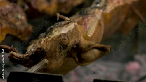 half pig on a spit turns slowly roasting it