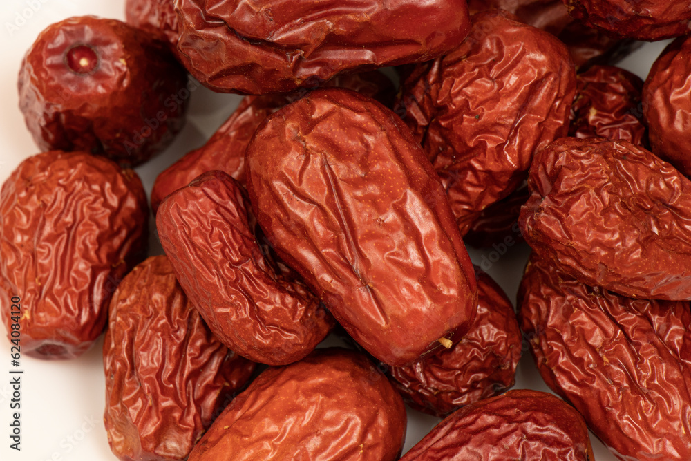 Dried jujube seeds which are brown overlay on a white background. Jujube seeds is an ingredient in desserts, soups and drinks. Close-up Dried jujube seeds which are brown overlay on a white background. Jujube seeds is an ingredient in desserts, soups and drinks. Close-up