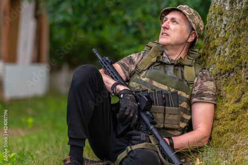 Obraz na płótnie A man with a gun laid-back looks into the distance w salonie