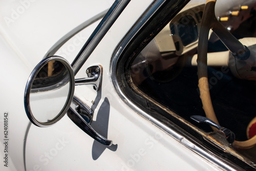 Chrome rearview mirror on a white retro car. Close-up. © Serhii