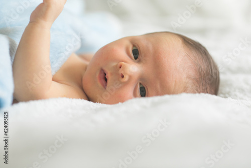 A cute newborn boy in the first days of life sleeps naked on a white fabric background.