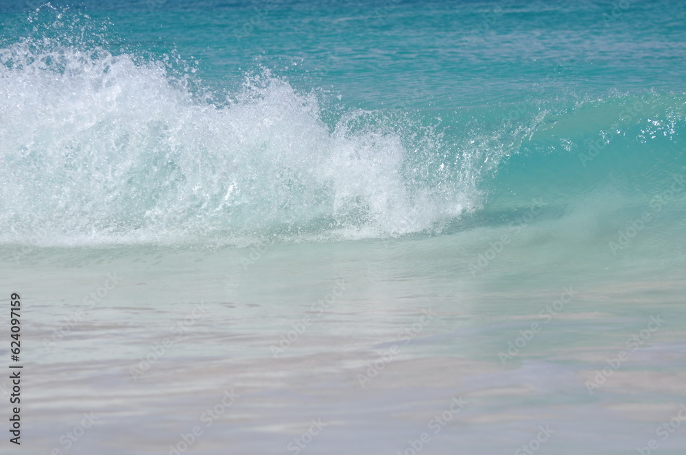 Tropische Energie: Eine sich brechende Welle am karibischen Strand der Bahamas mit türkisem klarem Wasser