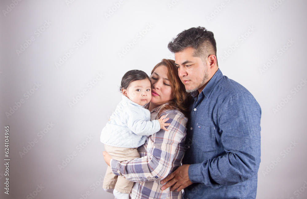 Beautiful photo of mom and dad holding baby on light photo studio background. Family and baby concept.