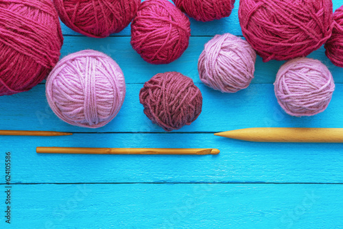 Hobbies and knitting concept. Pink balls of wool and knitting needles on blue rustic table. Copy space