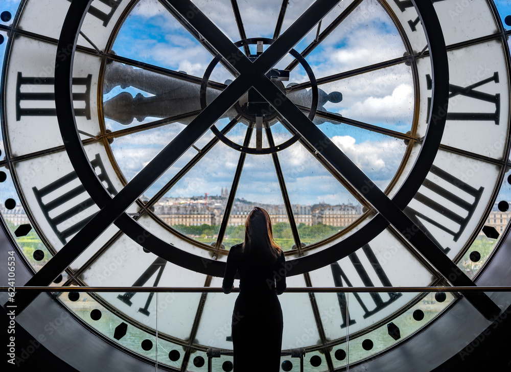 A girl standing in front of a huge clock overlooking a city