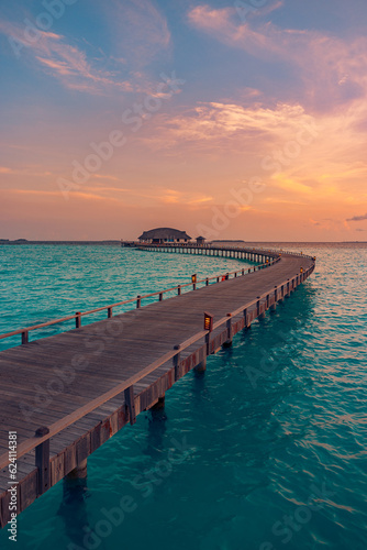 Fototapeta Naklejka Na Ścianę i Meble -  Maldives island sunset. Water bungalows villas resort at islands beach. Indian Ocean, Maldives. Long wooden pier path in luxury resort. Colorful sky sea clouds, calm relax nature. Peaceful reflections