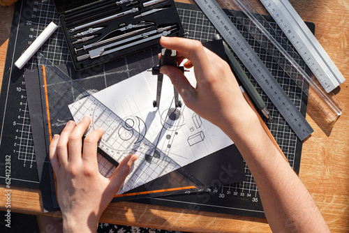 Architect and designer working accurately on a project drawing sketches and technical drafts on paper using professional tools like rulers compass and triangle logo design top view over the shoulder