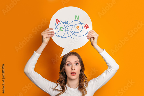 young shocked female student holding paper speech bubble paper isolated over orange background photo
