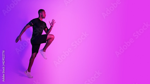 Fototapeta Naklejka Na Ścianę i Meble -  Black Athlete Guy Jumping Exercising During Training On Purple Background