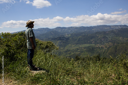 senior man on the mountain peak looking on mountain valley with sunbeams at colorful sunset in autumn in colombia