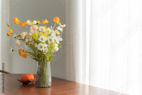 cozy and elegant home interior with modern furniture and stylish decor. Add touch of nature with orange and artificial floral bouquet in a white vase. luxury and relaxation in residential concept.