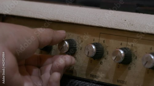 adjusting knobs on guitar amplifier.