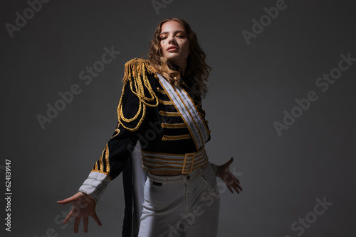 A glamorous blonde in a carnival uniform with epaulettes, posing with pretentious poses, a show host or a pop artist