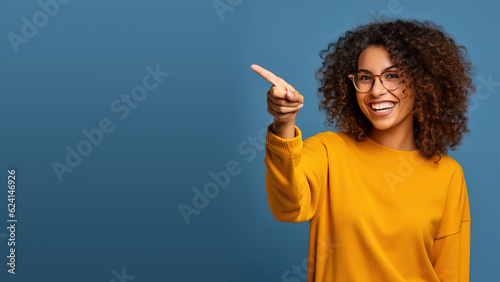 Beautiful young black woman pointing up to copy space and smiling, happy, Pretty girl act like satisfied at the product, use for advertising , isolated on blue background photo