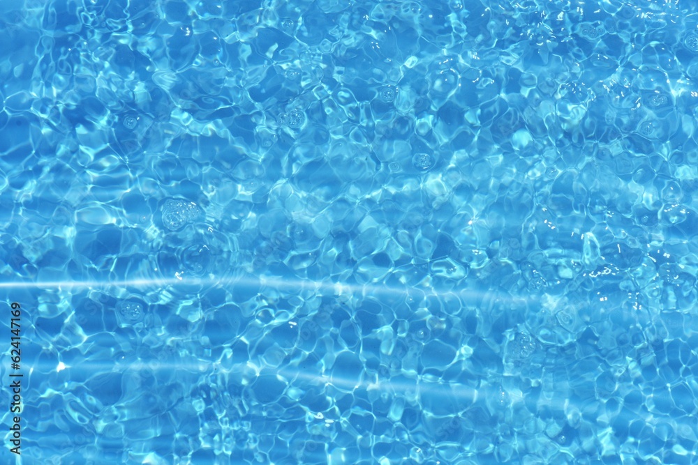 Blue water with ripples on the surface. Defocus blurred transparent blue colored clear calm water surface texture with splashes and bubbles. Water waves with shining pattern texture background.