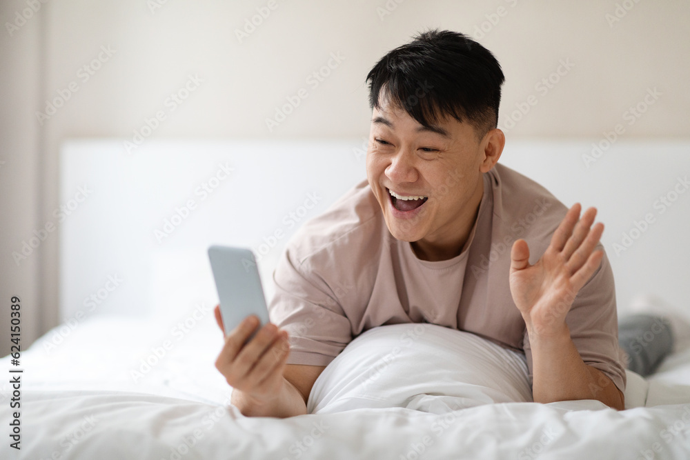 Thrilled relaxed asian man have video call with friends Thrilled relaxed asian man have video call with friends