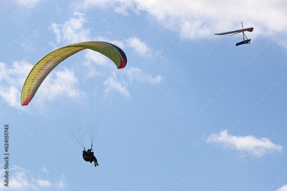 Tandem Paraglider and hang glider flying in a blue sky Tandem Paraglider and hang glider flying in a blue sky