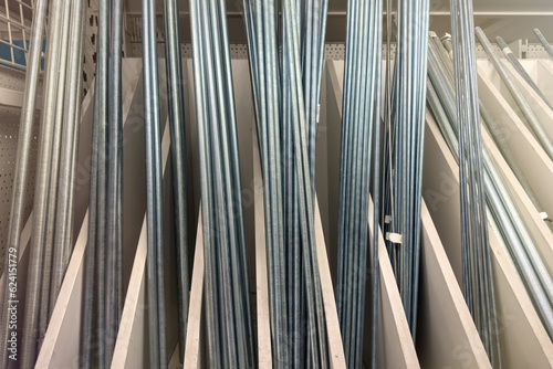 Threaded rods or threaded studs. Galvanized metal rod with threads along the entire length. Long threaded studs of different thicknesses in a hardware store.